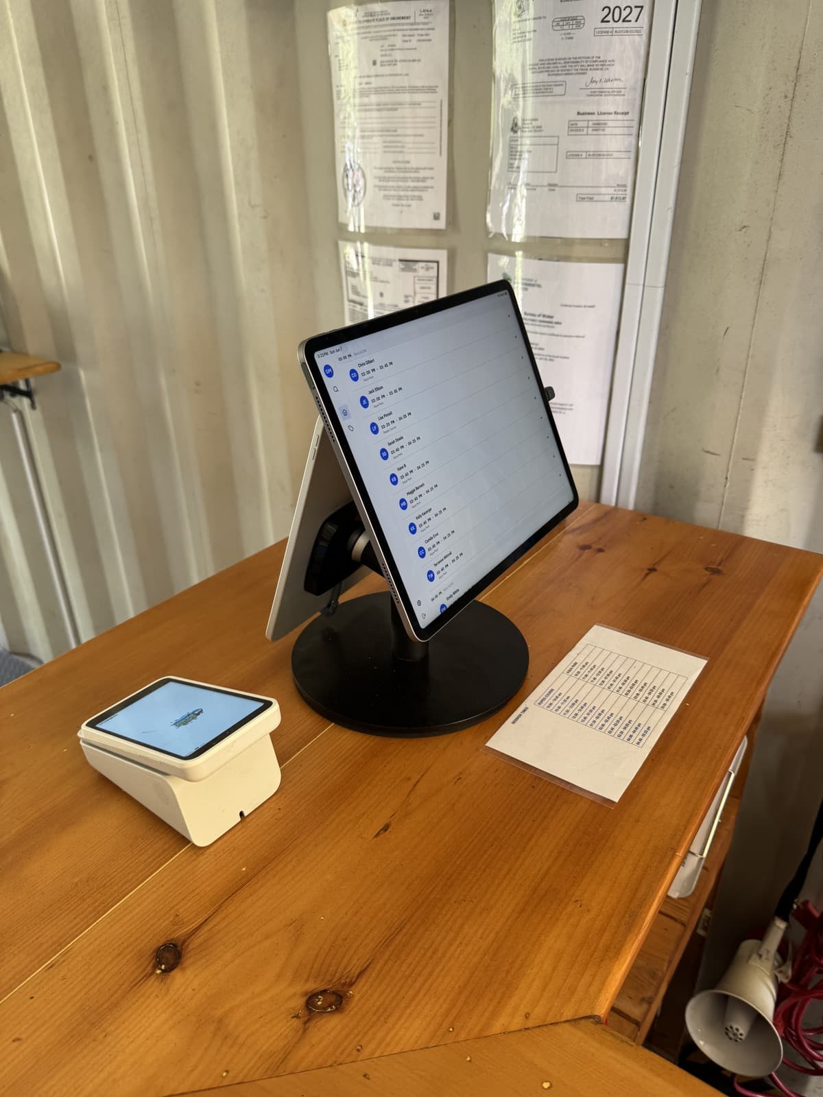 The staff side of the same stand — the cashier's iPad showing the booking and check-in list